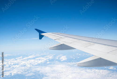 Aircraft Wing on beautiful blue sky and cloud background in altitude during flight. Wing of an airplane looking from the window.