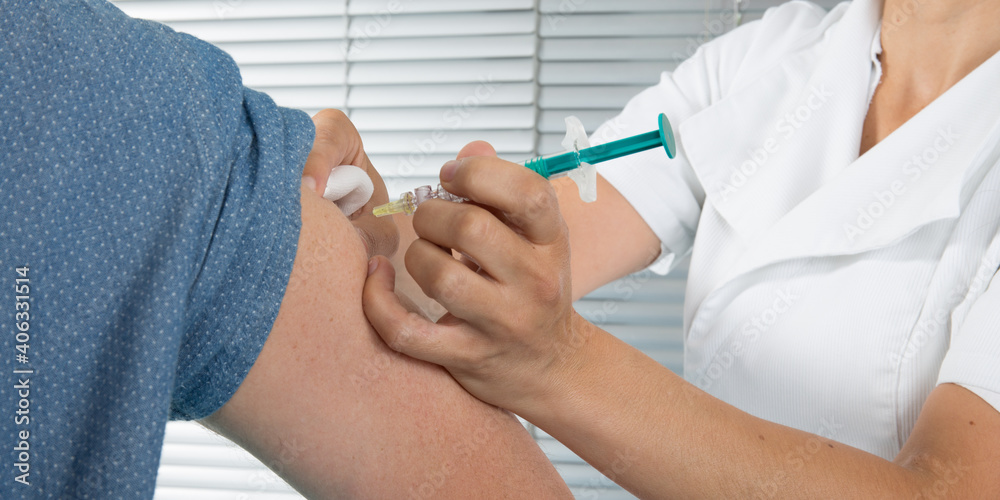 Cleaning up patient arm ready for a vaccine woman doctor giving an injection to man Cleaning up patient arm ready for a vaccine woman doctor giving an injection to man