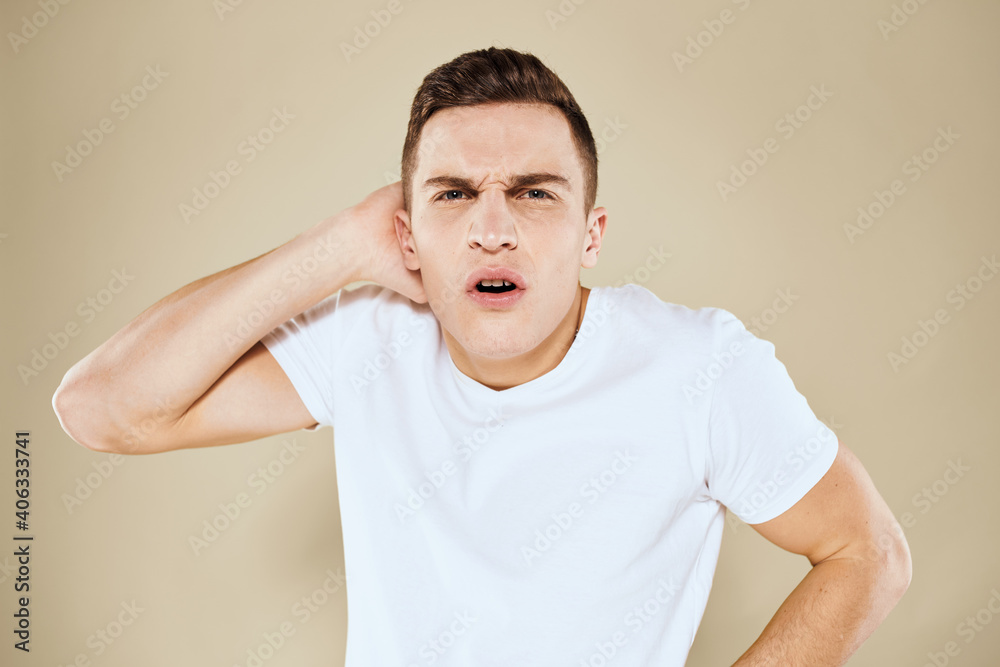 Emotional man facial expression gesture with hands white t-shirt beige background Emotional man facial expression gesture with hands white t-shirt beige background