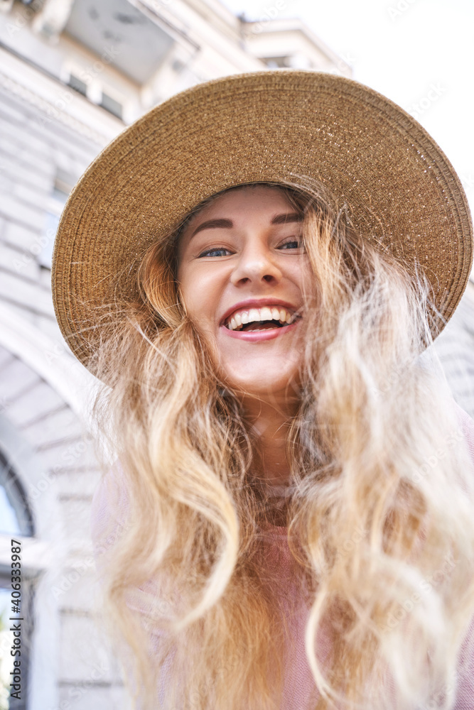 Young woman portrait in hat. Upside. Outdoors cafe. Summer happy people face at town. Pretty blond person on vacation. Staycation. Look straight. Cute long hair. Lifestyle laughing. Dental concept