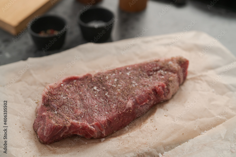 closeup raw seasoned new york steak on concrete countertop background