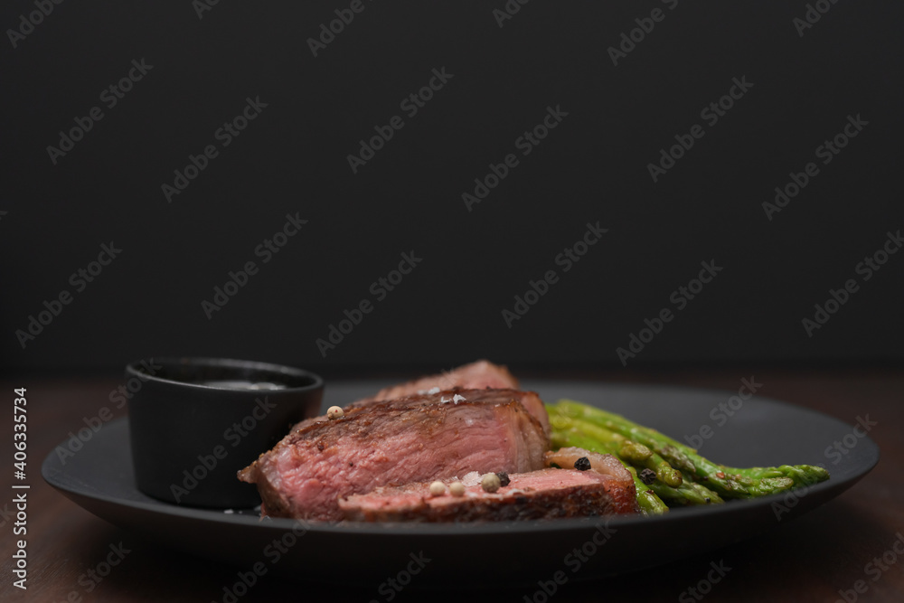 New york steak with asparagus on black plate with pesto New york steak with asparagus on black plate with pesto