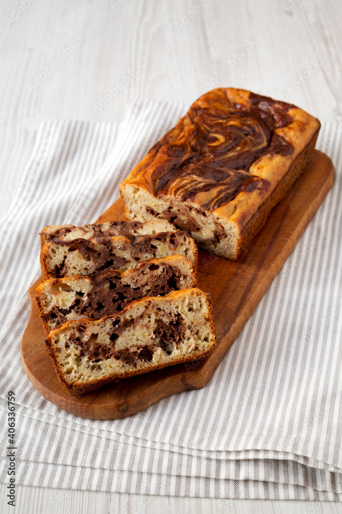 Homemade Chocolate Banana Bread on a rustic wooden board on a white wooden table, side view.