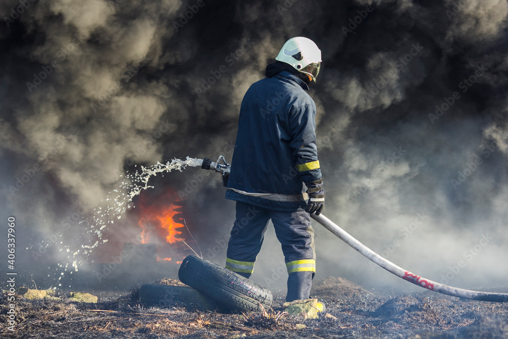 Obraz premium Firefighters extinguish a fire. Lifeguards with fire hoses in smoke and fire