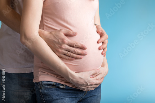mother and father hold hands on pregnant mother's stomach © savva_25