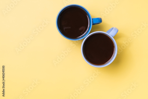 Top view of two coffee mugs on a yellow background.