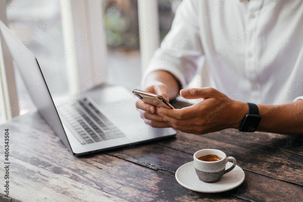 man hand use phone and laptop connecting wifi internet, sitting at wooden table in coffee shop man hand use phone and laptop connecting wifi internet, sitting at wooden table in coffee shop