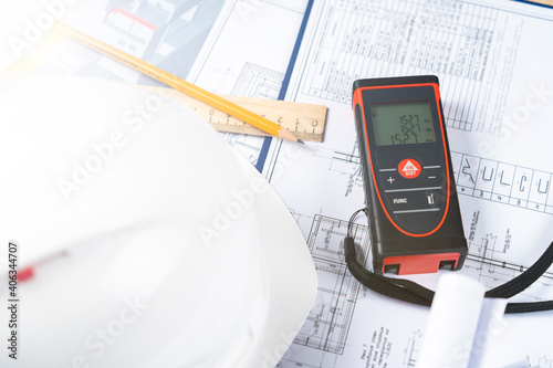 helmet and tools for construction drawings and construction drawings and laser rangefinder for distance measurements, close-up, selective focus, tinted image,