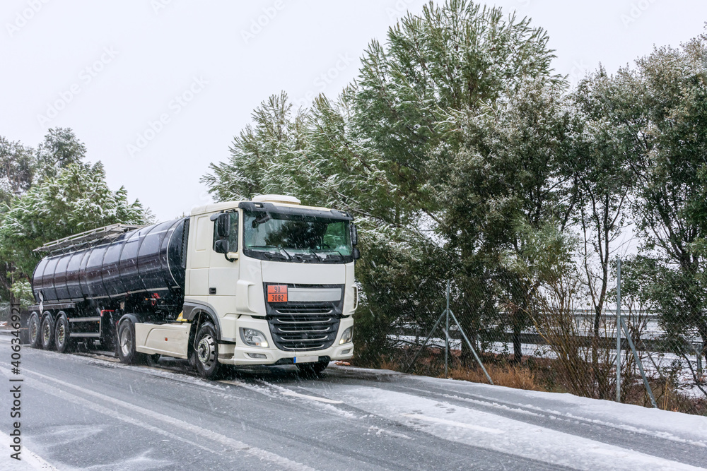 Fuel tanker parked in a freeway parking lot on a day complicated by the falling snow. Fuel tanker parked in a freeway parking lot on a day complicated by the falling snow.