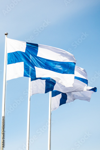 Three finnish national flags on the wind against the blue sky