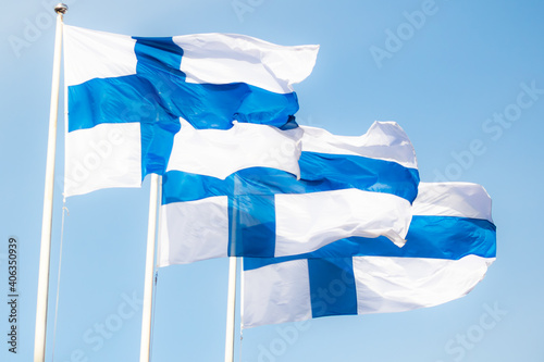 Three finnish national flags on the wind against the blue sky