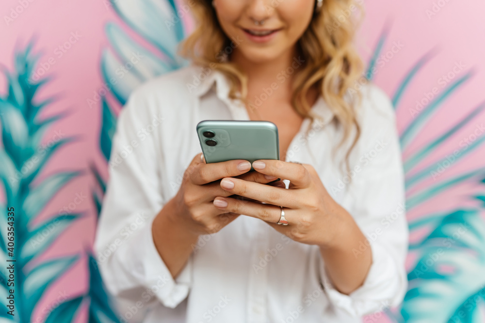 Woman typing text message on smart phone in a cafe. Cropped image of young woman sitting at a table using mobile phone. Woman typing text message on smart phone in a cafe. Cropped image of young woman sitting at a table using mobile phone.