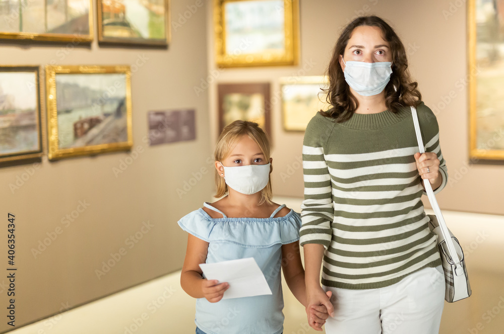 Mom and daughter in protective masks inspect the exhibits of the museum