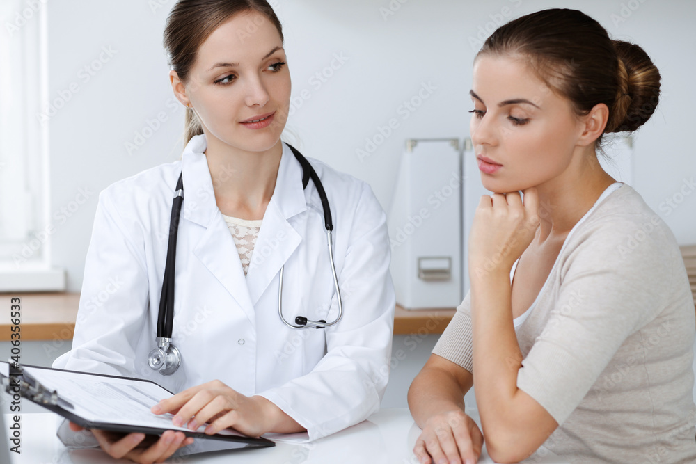 Doctor and patient are sitting and discussing health examination results in clinic office. Health care, medicine and good news concepts Doctor and patient are sitting and discussing health examination results in clinic office. Health care, medicine and good news concepts