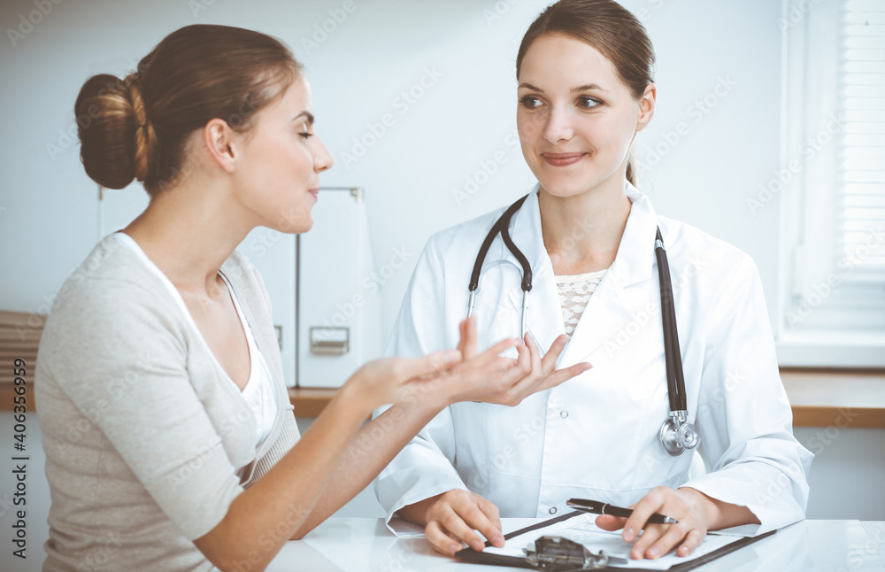 Doctor and patient are sitting and discussing health examination results in clinic office. Health care, medicine and good news concepts Doctor and patient are sitting and discussing health examination results in clinic office. Health care, medicine and good news concepts