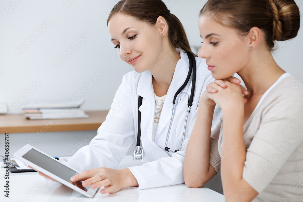 Doctor and patient are sitting and discussing health examination results while using tablet computer. Health care, medicine and good news concepts