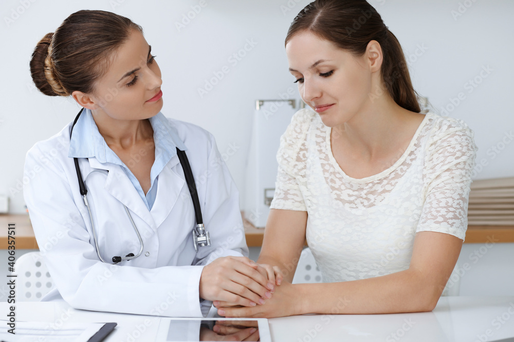 Woman-doctor reassuring her female patient while sitting at the desk. Medicine concept Woman-doctor reassuring her female patient while sitting at the desk. Medicine concept