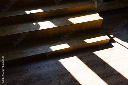 steps of a wooden staircase in front of the exit. the interior of the room is illuminated by bright rays of light