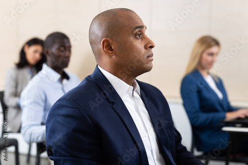 Portrait of attentive Hispanic businessman on training business session in lecture hall. Concept of education and staff development