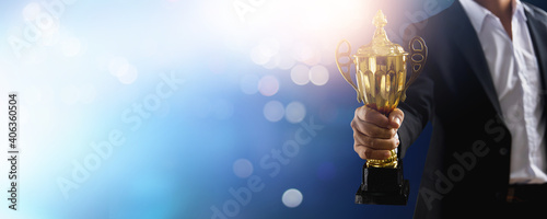 champion of the best and achievement, winner or victory concept, celebration to successful businessman celebrate in success business holding golden award on soft blue background with bokeh photo
