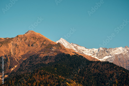 Beautiful brown mountains with snow-capped peaks against a blue sky. Natural wallpaper. © dvulikaia