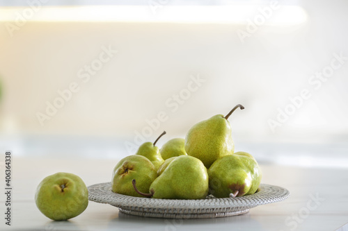 Plate with fresh ripe pears on white table