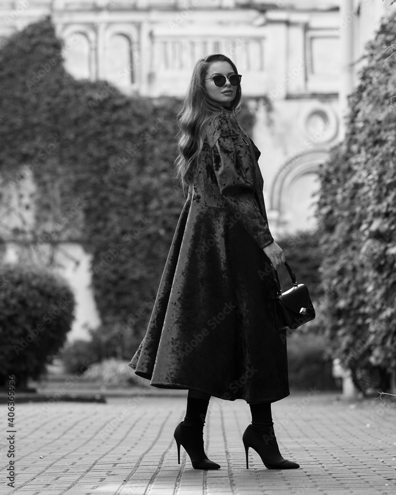Stylish woman in red long coat with belt, black skirt, tights, sunglasses and high heels walking at city street. Brunette caucasian girl with long wavy hair outdoor portrait Stylish woman in red long coat with belt, black skirt, tights, sunglasses and high heels walking at city street. Brunette caucasian girl with long wavy hair outdoor portrait