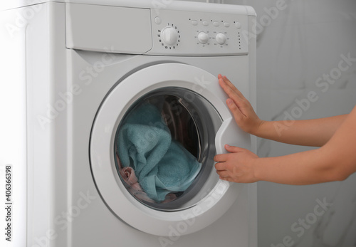 Woman opening modern washing machine indoors, closeup