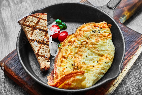 omelet with tomatoes and white onions in a black pan and a slice of rye bread. Healthy breakfast with your own hands