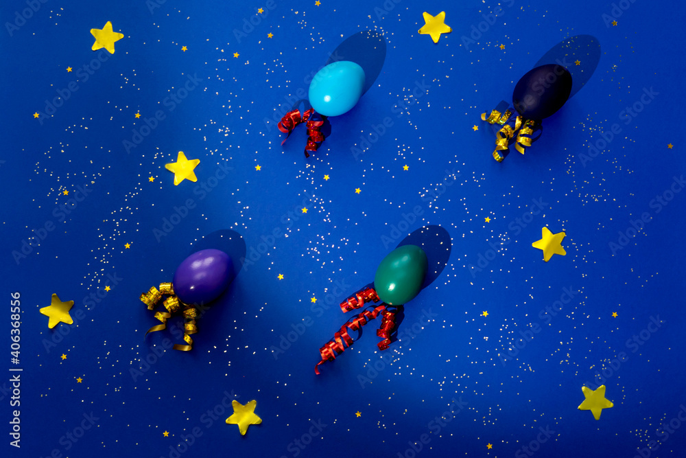 Color easter eggs as rockets over blue background. Easter festive cosmic concept. Flat lay.
