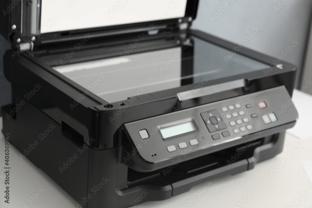 Open modern printer with control panel on white table, closeup Open modern printer with control panel on white table, closeup
