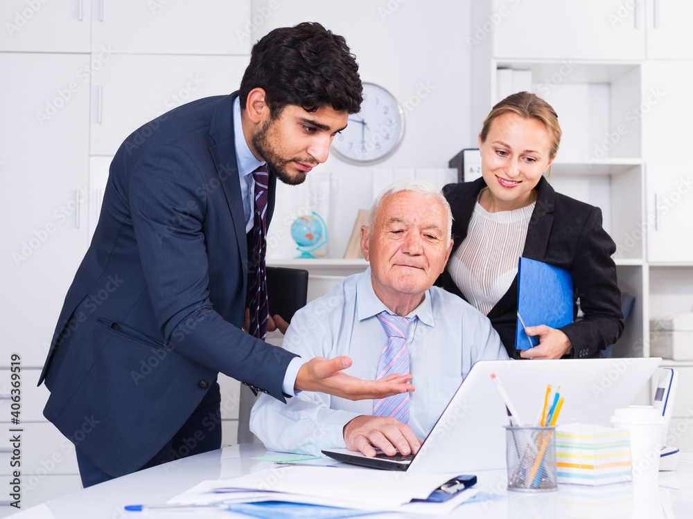 Obraz premium Employees are demonstrating reports on laptop to mature boss in the office.