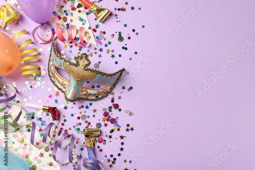 Beautiful carnival mask and party decor on violet background, flat lay. Space for text