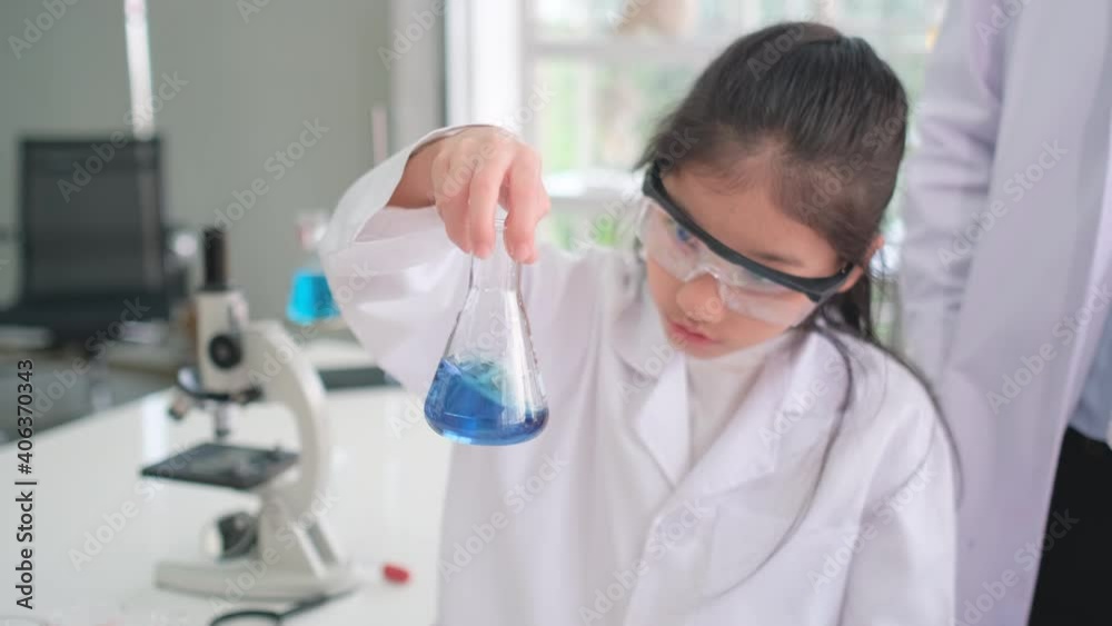 Young scientist girl express exciting after experiment with blue chemical in flask in laboratory or classroom with teacher and classmate. Young scientist girl express exciting after experiment with blue chemical in flask in laboratory or classroom with teacher and classmate.