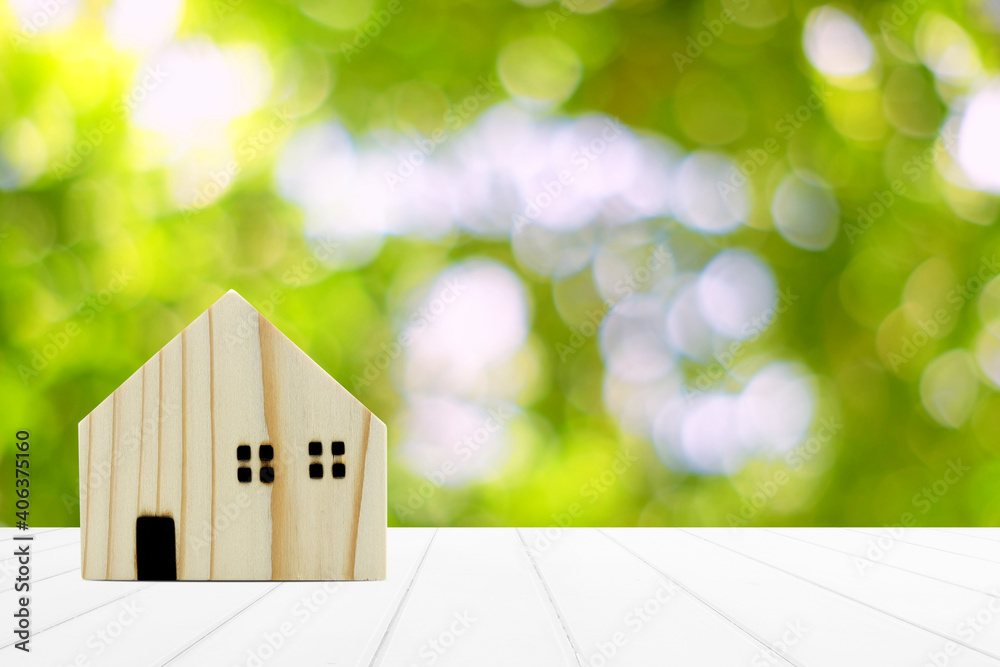 Wooden Miniature House on White Wooden Table and Beautiful Bokeh in the Garden Background with Space for Text.