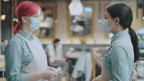 Bistro workers in protective masks talking, food establishment during covid-19