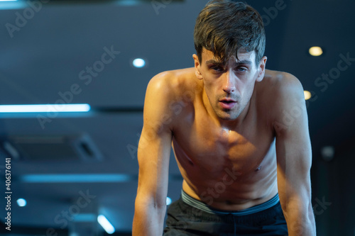 Muscular caucasian athlete male sweating tired after exercise at fitness gym
