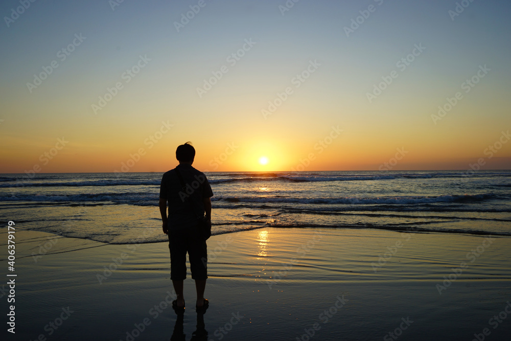 Man standing on Nusa Dua Beach at dusk, Beautiful sunset, Bali island, Indonesia