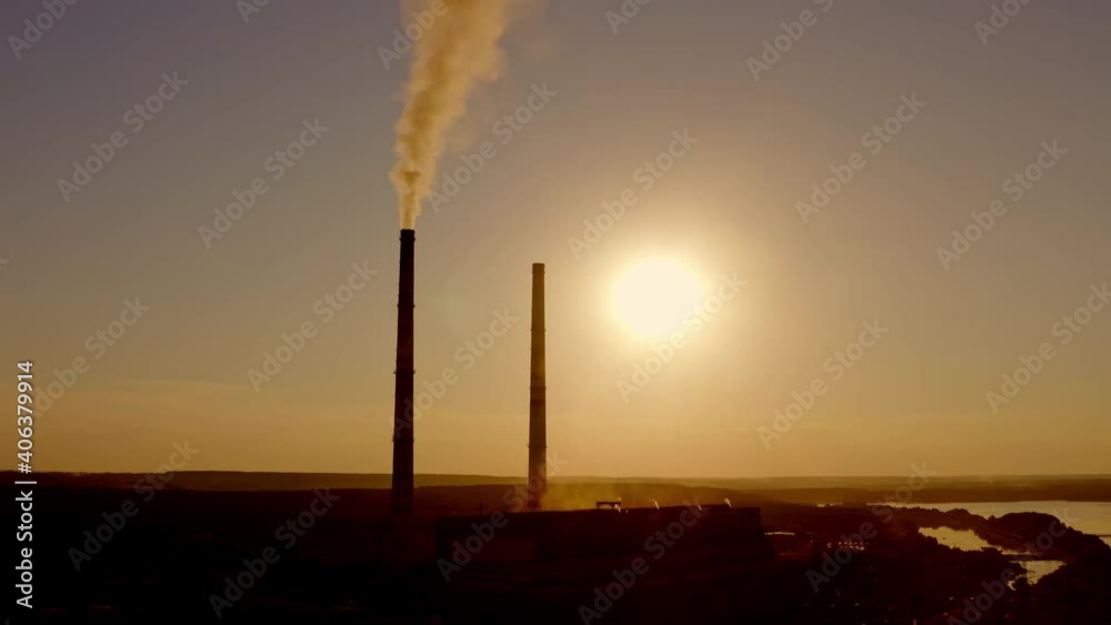 Silhouette of tower pipes with harmful fumes at sunset. Dark industrial chimneys releasing toxic emissions in the air from power plant among nature. Silhouette of tower pipes with harmful fumes at sunset. Dark industrial chimneys releasing toxic emissions in the air from power plant among nature.