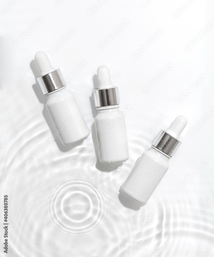 White cosmetic bottles on the water surface. Summer water pool fresh concept. Flat lay, top view. White cosmetic bottles on the water surface. Summer water pool fresh concept. Flat lay, top view.