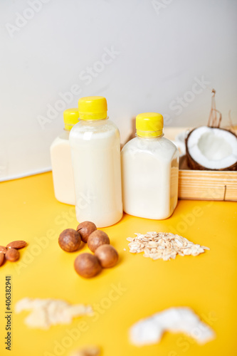 Alternative types of vegan milks in bottles on a yellow background