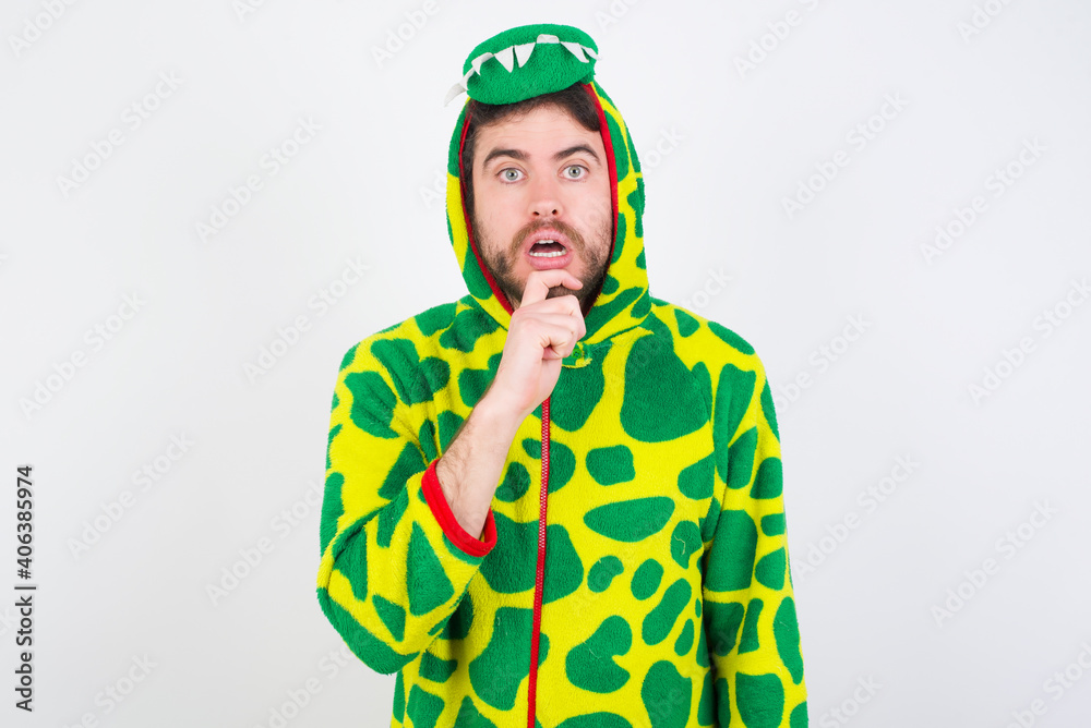 Fototapeta premium Nervous puzzled Young caucasian man wearing a pajama standing against white background opens mouth from surprise, reacts on sudden news.