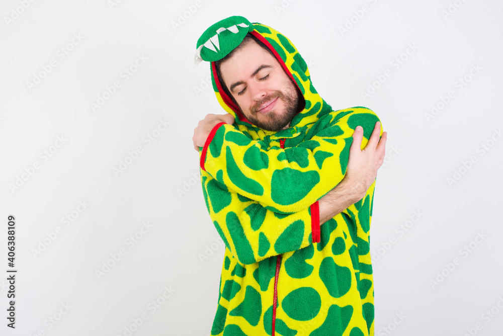 Fototapeta premium Young caucasian man wearing a pajama standing against white background Hugging oneself happy and positive, smiling confident. Self love and self care