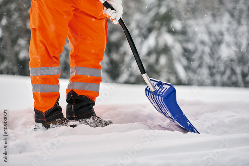 Kommunaler Service Arbeiter in oranger Sicherheitsuniform reinigt Wege und Straßen nach Schneefall photo