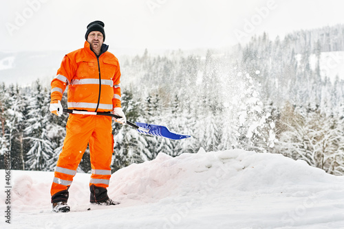 Kommunaler Service Arbeiter in oranger Sicherheitsuniform reinigt Wege und Straßen nach Schneefall photo