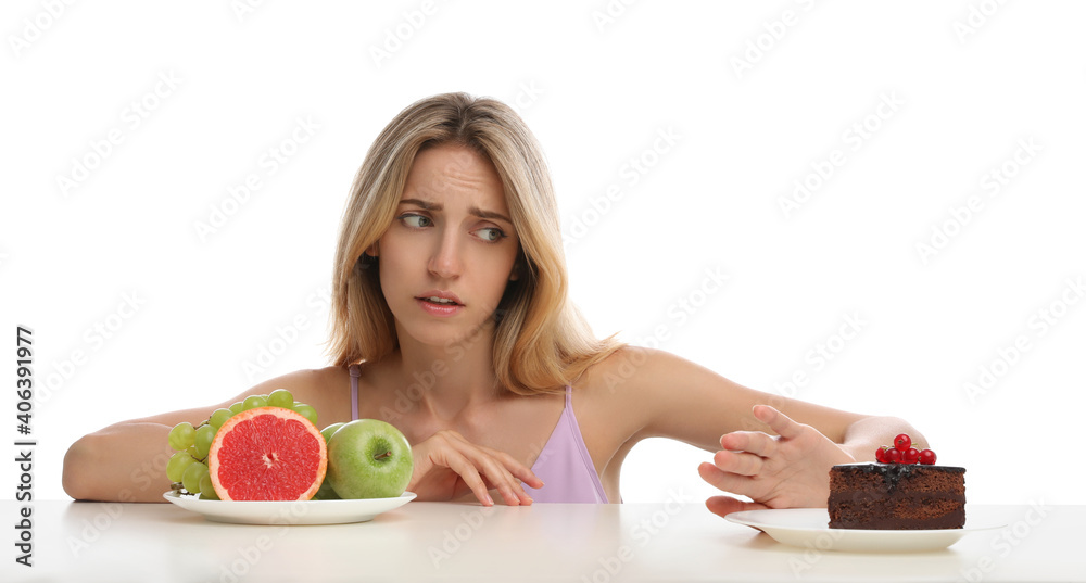 Woman choosing between cake and healthy fruits at table on white background Woman choosing between cake and healthy fruits at table on white background