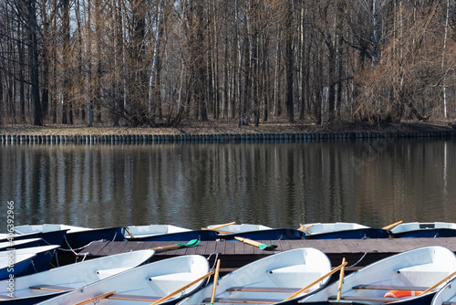 A pier for boats on a pond in early spring on a sunny day - many boats near a wooden boat dock