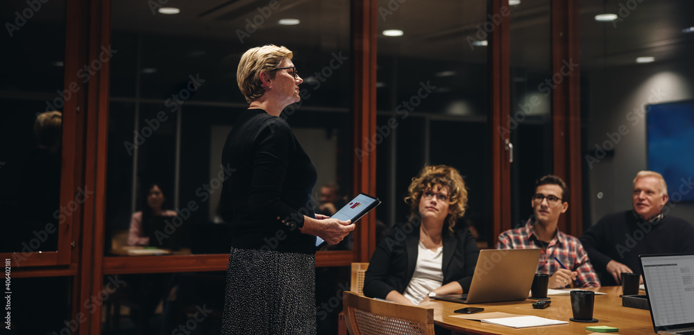 Businesswoman addressing team in office boardroom