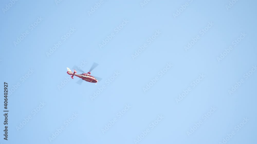 Rescue Helicopter Hovering Overhead With Blue Sky In Background In Tokyo, Japan. - low angle Rescue Helicopter Hovering Overhead With Blue Sky In Background In Tokyo, Japan. - low angle