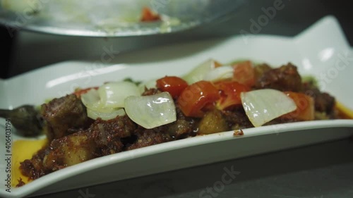 Garnishing The Plate Of Pork Binagoongan With Onions And Tomatoes. - close up photo